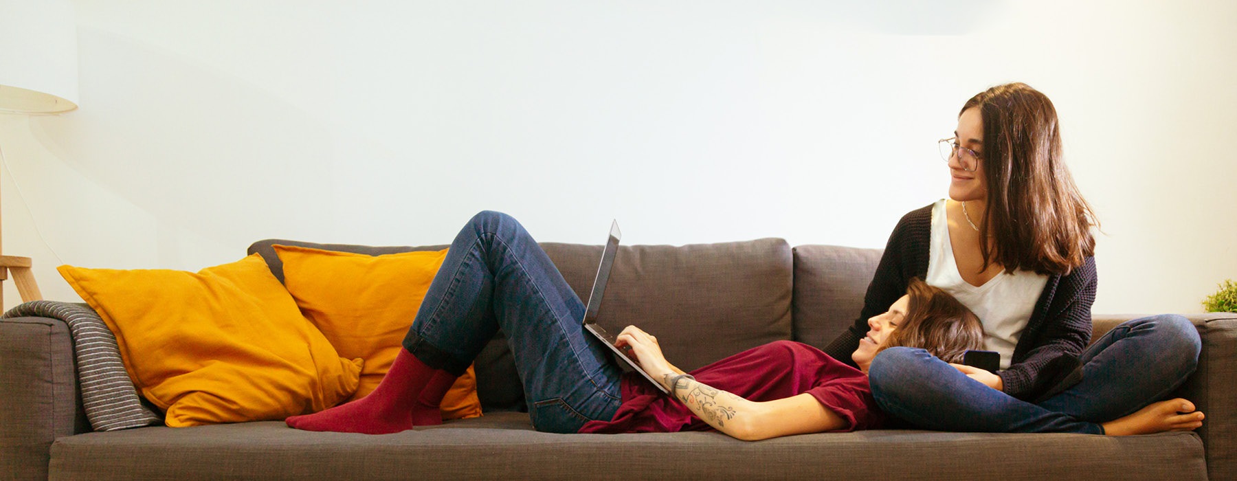 sisters look at a laptop on a couch