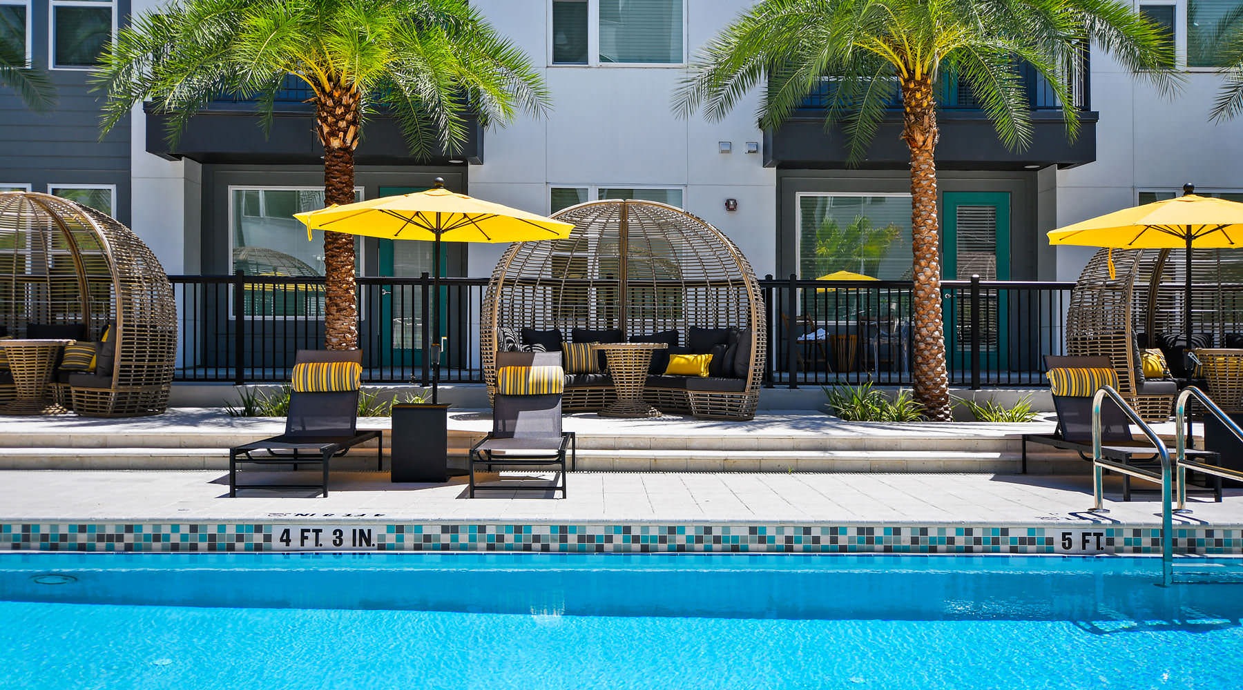 a pool with chairs and umbrellas by a building
