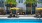 a pool with chairs and umbrellas by a building